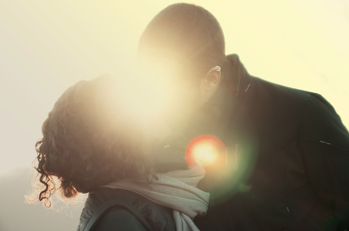 Backlit couple kissing with bright lens flare