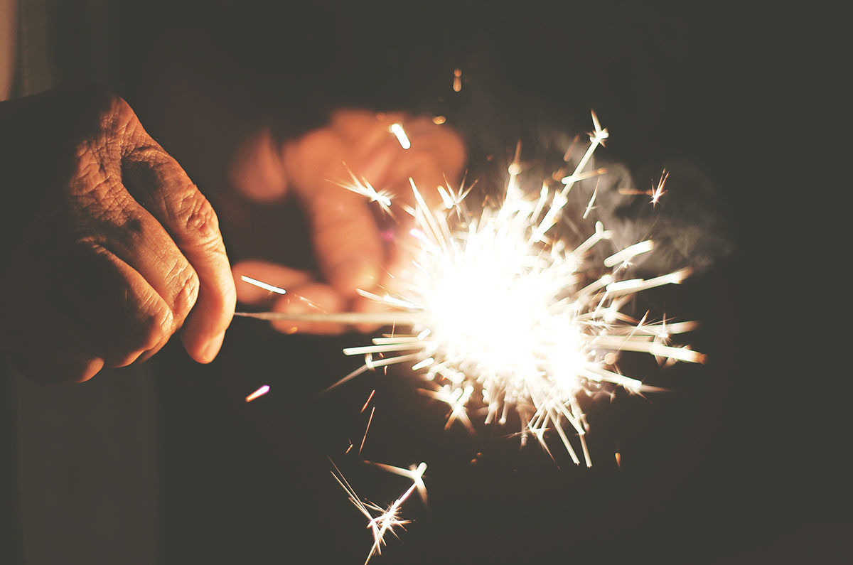 Hands holding a bright sparkler at night