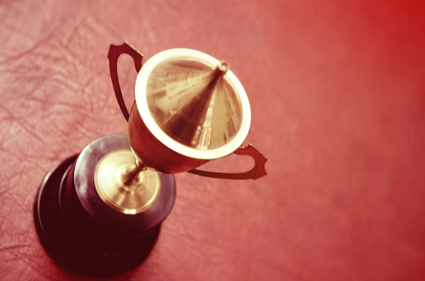 angled gold trophy on red textured background